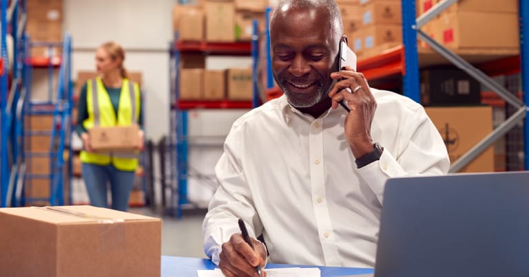 broker on the phone on a warehouse near racking system