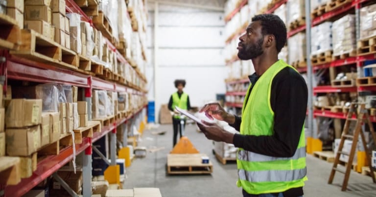 freight warehouse storage with worker checking on stocks on racks