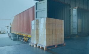 Pallets of packaged freight ready to be loaded into a truck at a warehouse dock.
