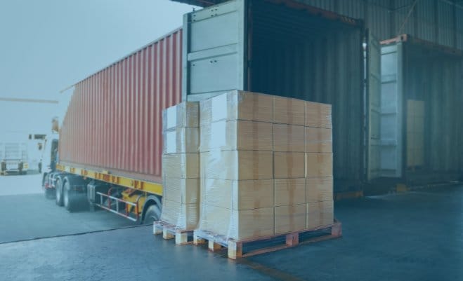 Pallets of packaged freight ready to be loaded into a truck at a warehouse dock.