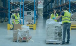 Freight teams in yellow vests sorting and checking boxes during peak season in a warehouse aisle.