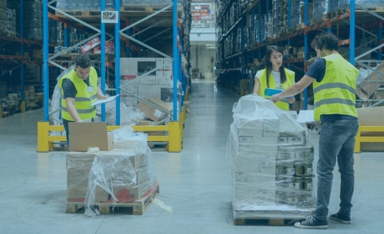 Freight teams in yellow vests sorting and checking boxes during peak season in a warehouse aisle.
