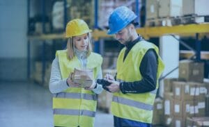 Two warehouse workers in safety gear checking a package to streamline freight workflow.