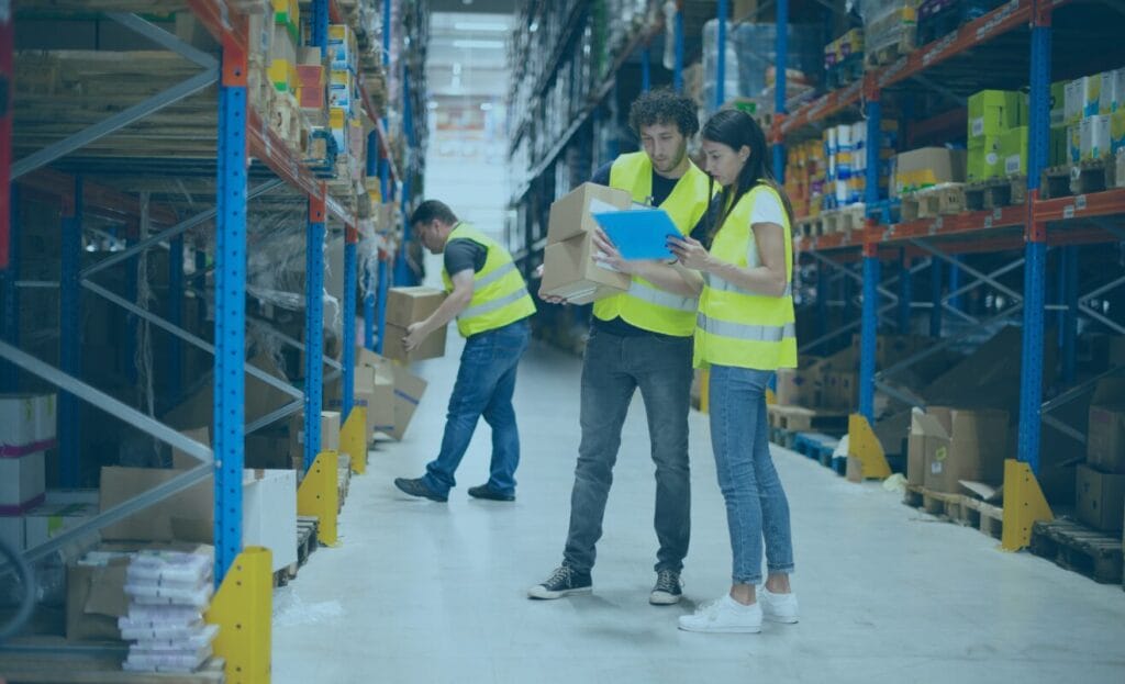 Warehouse workers in safety vests check inventory and watch for common freight overcharge issues.