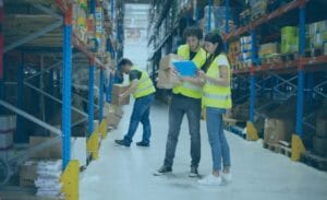Warehouse workers in safety vests check inventory and watch for common freight overcharge issues.